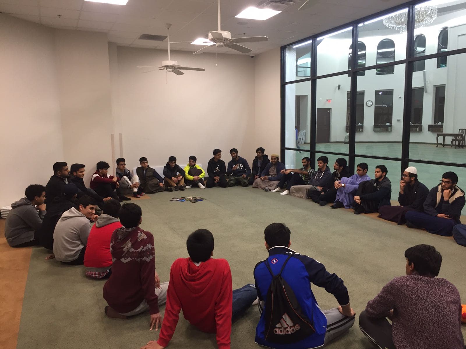 Students seated in a large circle for an evening halaqah