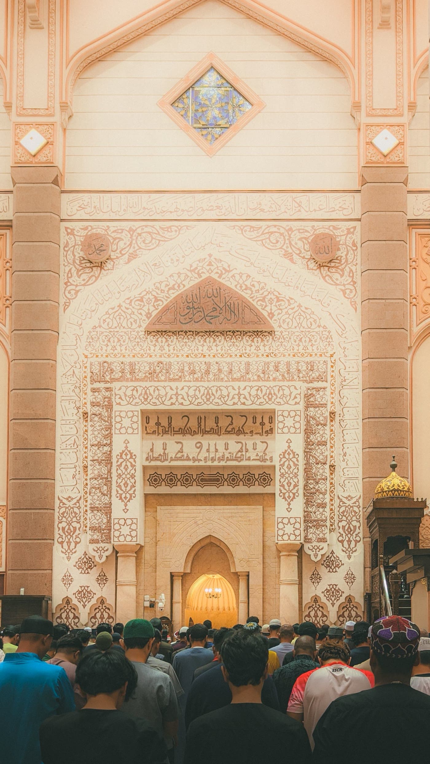 Worshippers gathered before an ornate mosque mihrab